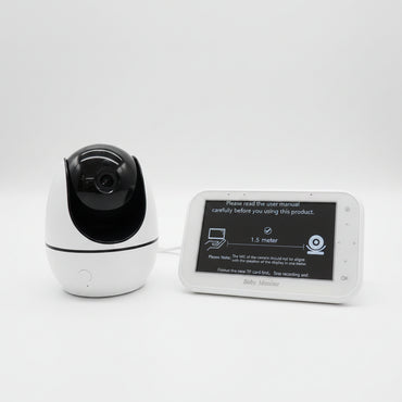 Bela rotirajuća pametna kamera bebi monitor sa crnim gornjim delom za objektiv pored horizontalnog bežičnog kontrolera sa ekranom od 4.3 inča i natpisom Baby Monitor.